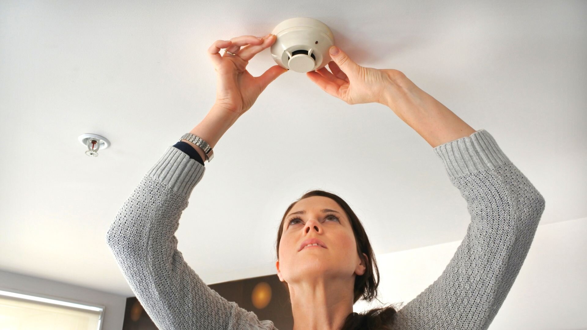 Woman Cleaning Smoke Alarm