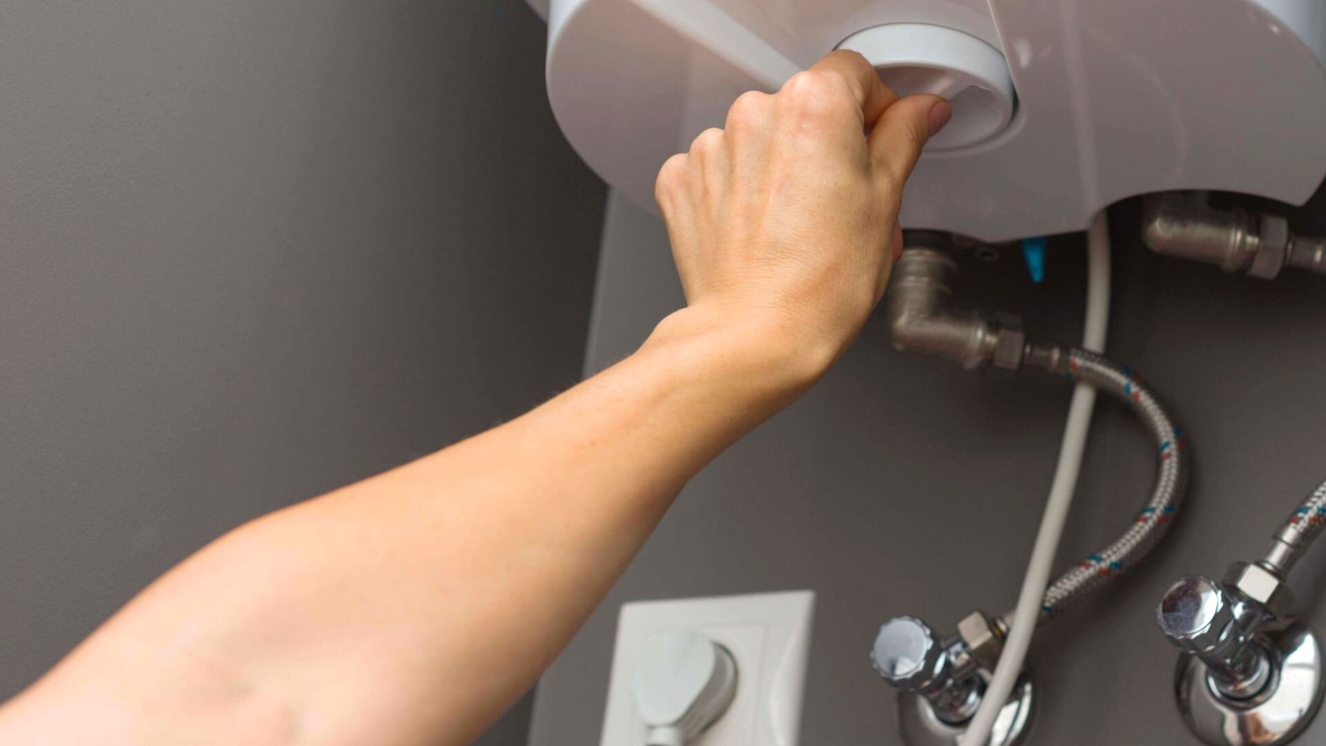 Person Turning Dial On Hot Water System 